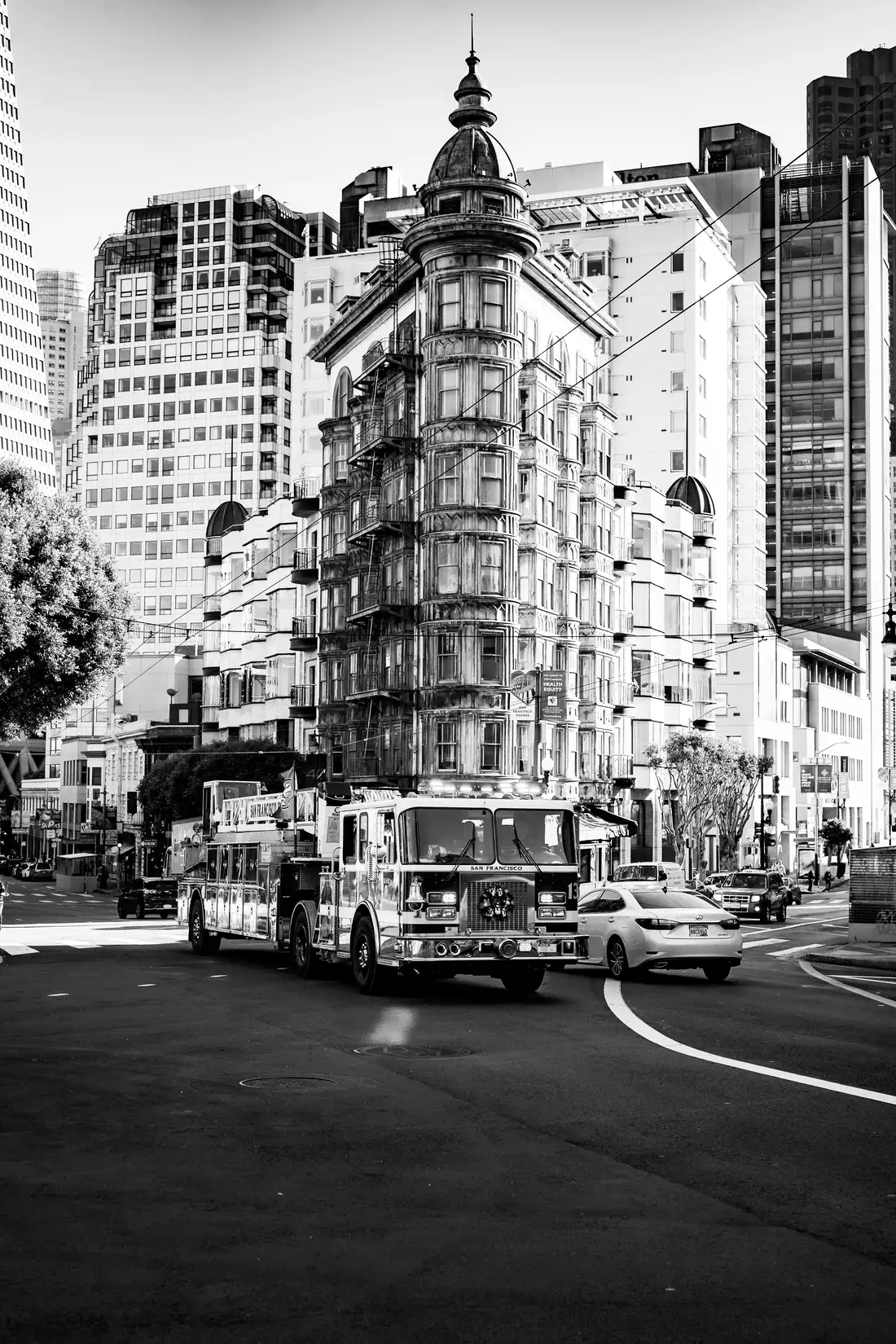Black-and-white photograph of a fire engine on a city street between tall buildings